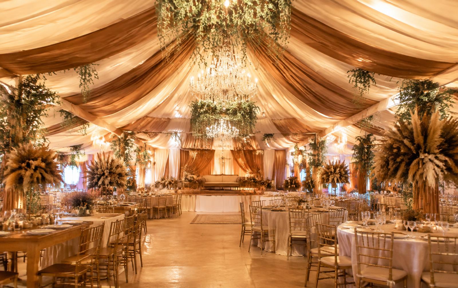 Draped tent celebration with ivory and caramel fabric, warm chandeliers and floral styling